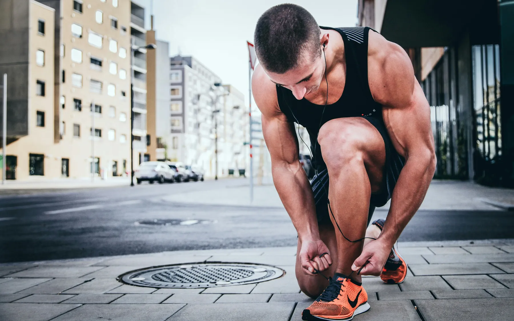 Man tying his running shoe on a city street